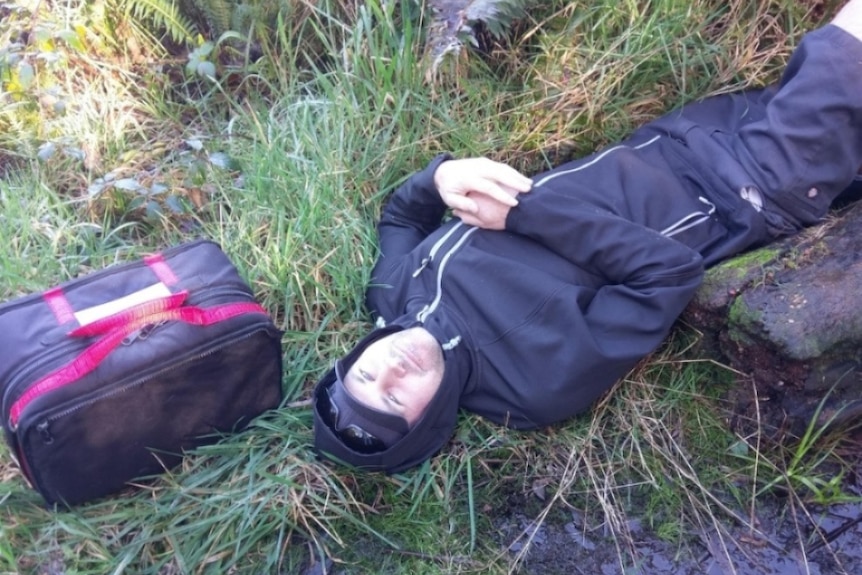  A man looks at the camera while lying on grass.