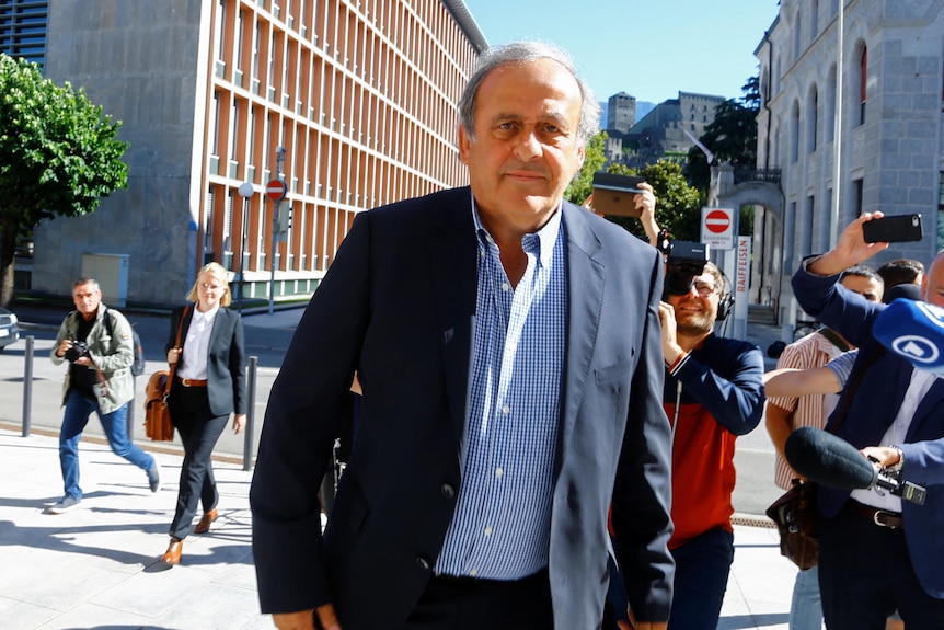 Michel Platini walks towards the camera with a neutral expression on his face