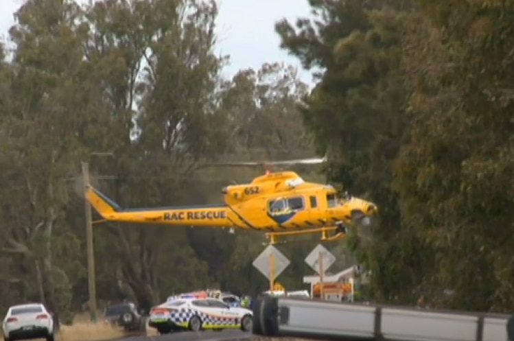 The yellow RAC rescue helicopter attends the scene of a crash on a country highway