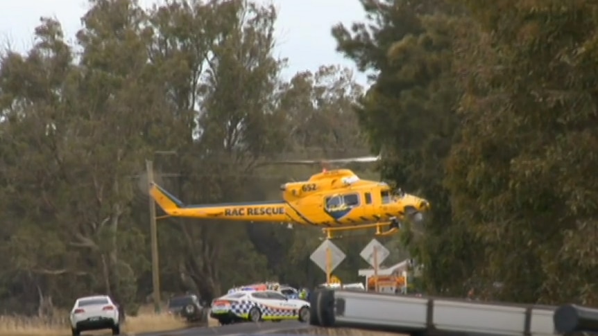 The yellow RAC rescue helicopter attends the scene of a crash on a country highway