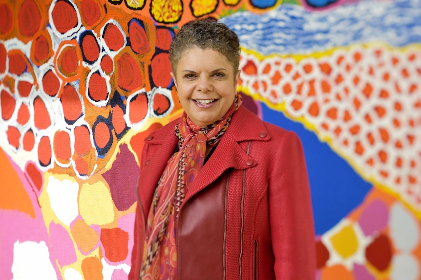 Deborah Cheetham standing in front of the Dulka Warngiid tapestry.