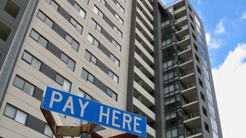 A tall apartment building with a pay parking sign in front of it.