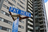 A tall apartment building with a pay parking sign in front of it.