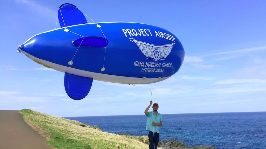 Kye Adams holding a blimp aloft, which is being trialled to look for sharks.
