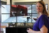 Woman stands in front of six-monitor interactive computer game