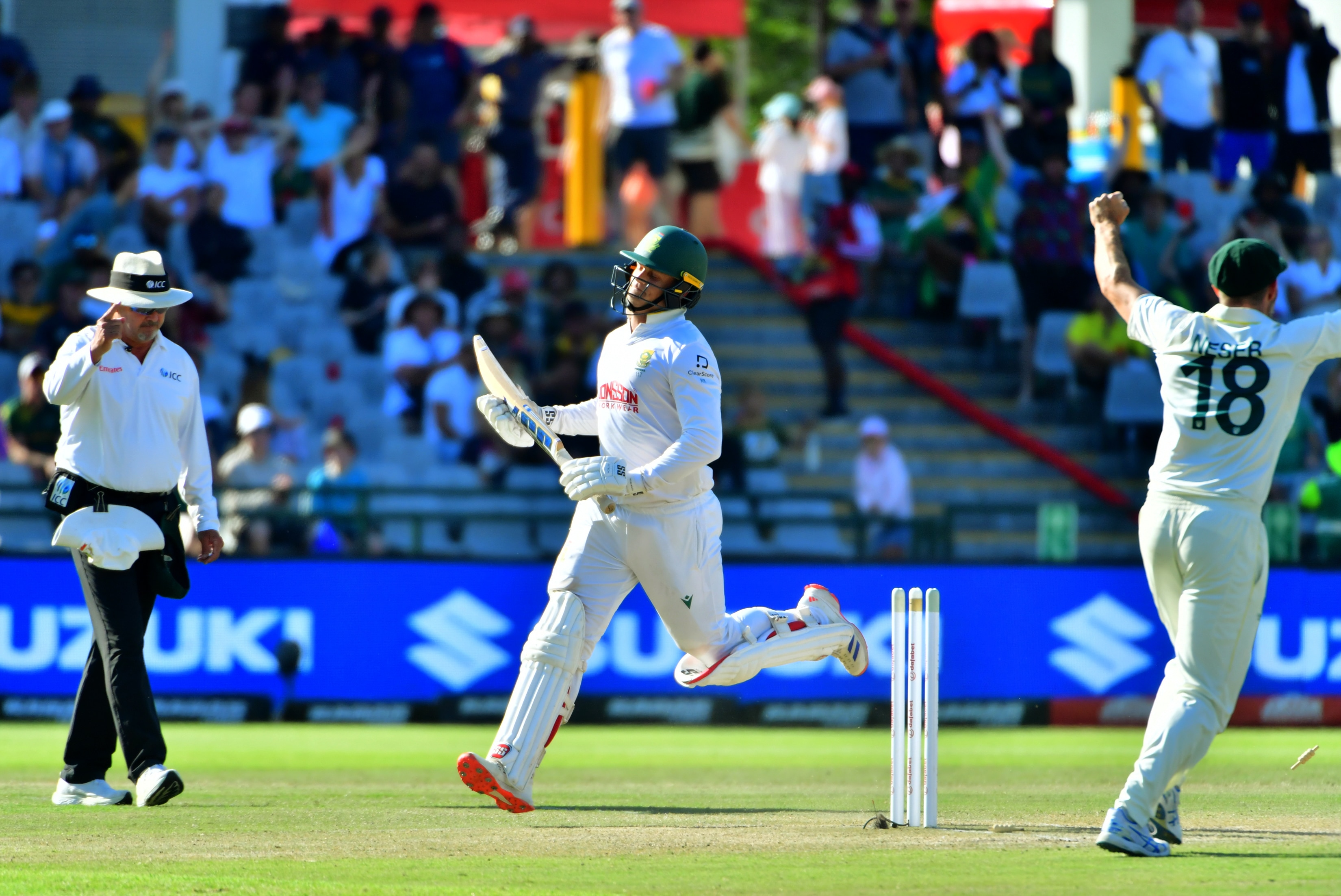 A frustrated South African batsman slows after being run out, as the umpire raises his finger and an Australian celebrates.