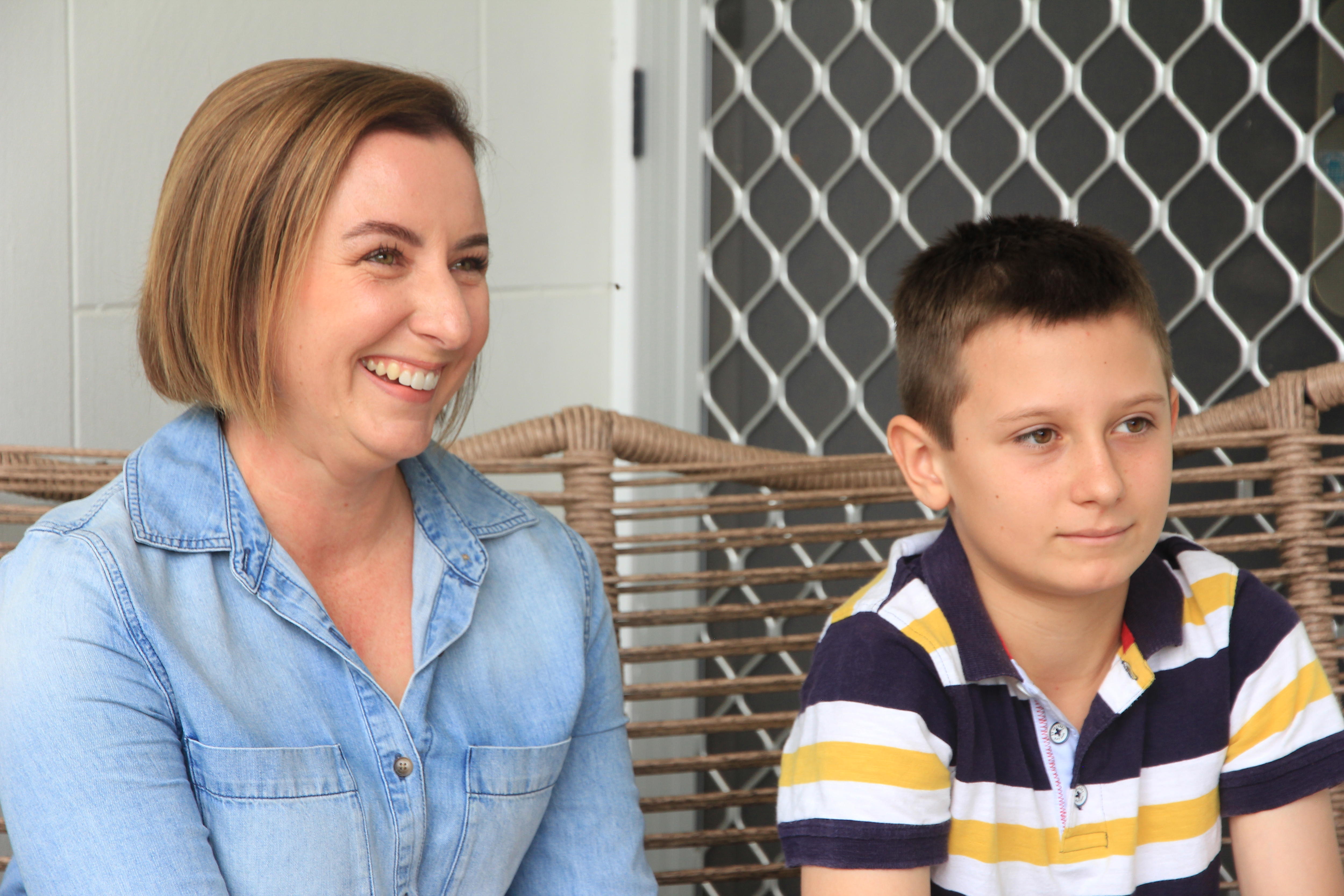 Una mujer sonriente sentada en un sofá al aire libre junto a un niño pequeño