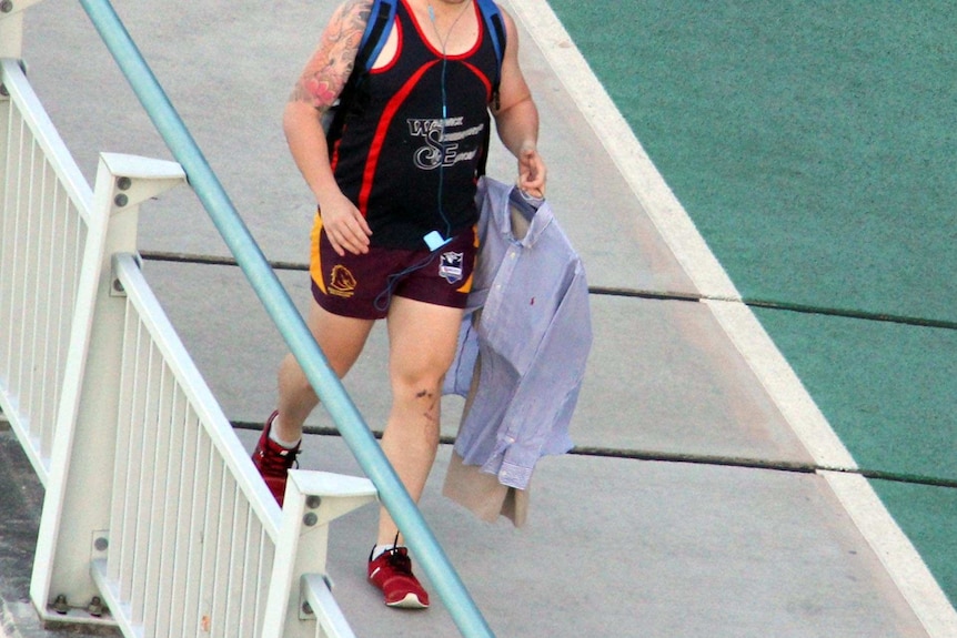 A man walks to work holding his work clothes.