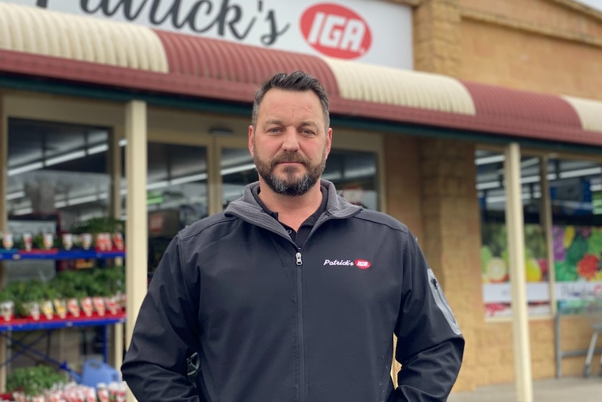 A man stands in front of a shop