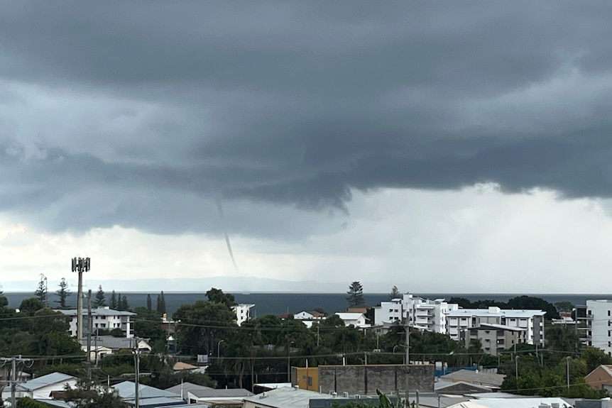 A waterspout over the ocean in the distance.