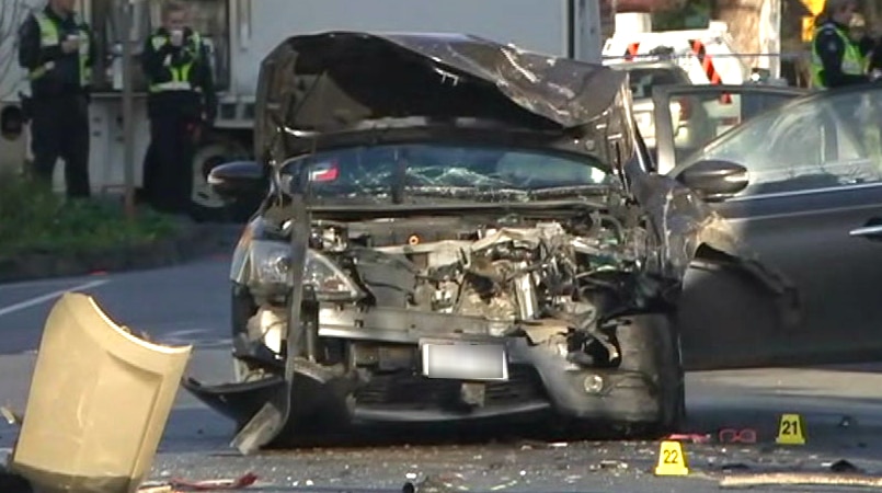 A car on a street in Collingwood with its bonnet smashed and crumpled, with glass and debris on the road.