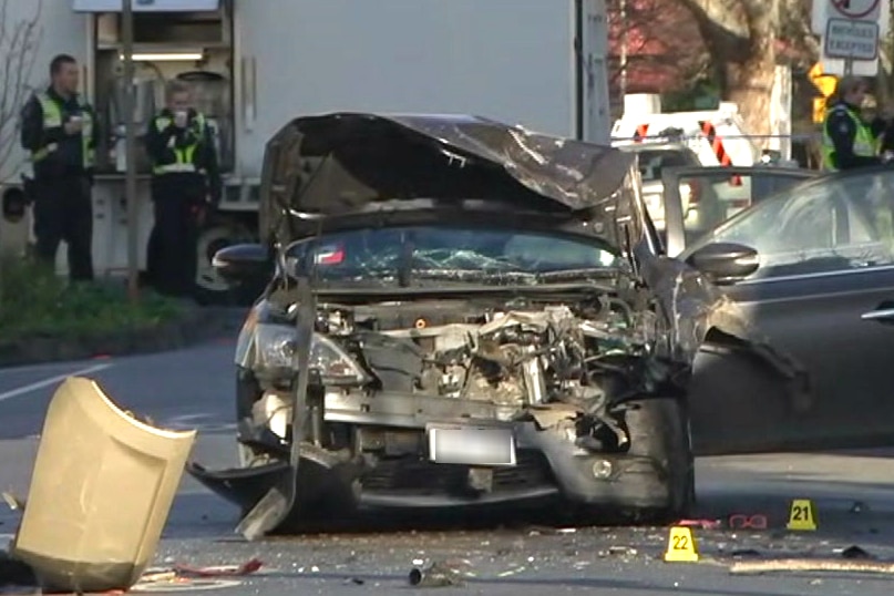 A car on a street in Collingwood with its bonnet smashed and crumpled, with glass and debris on the road.