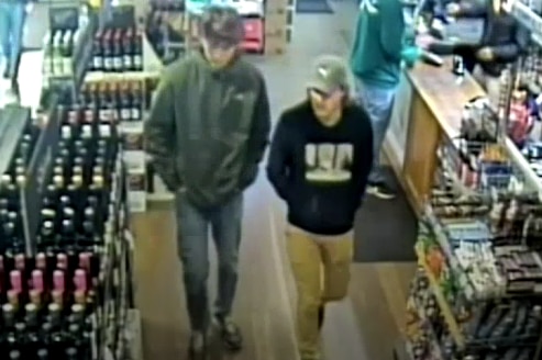 A young man in a bottleshop wearing a grey cap.