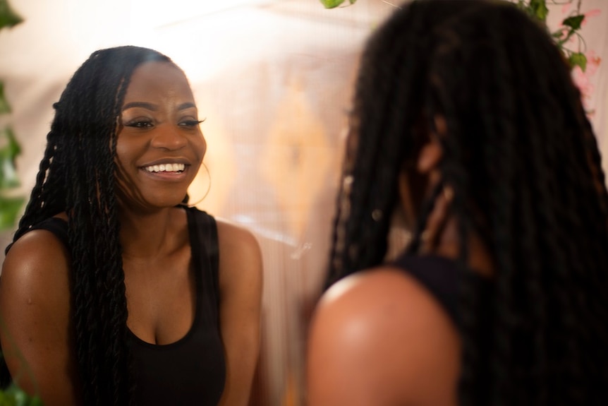 A young woman looks at herself in the mirror and smiles