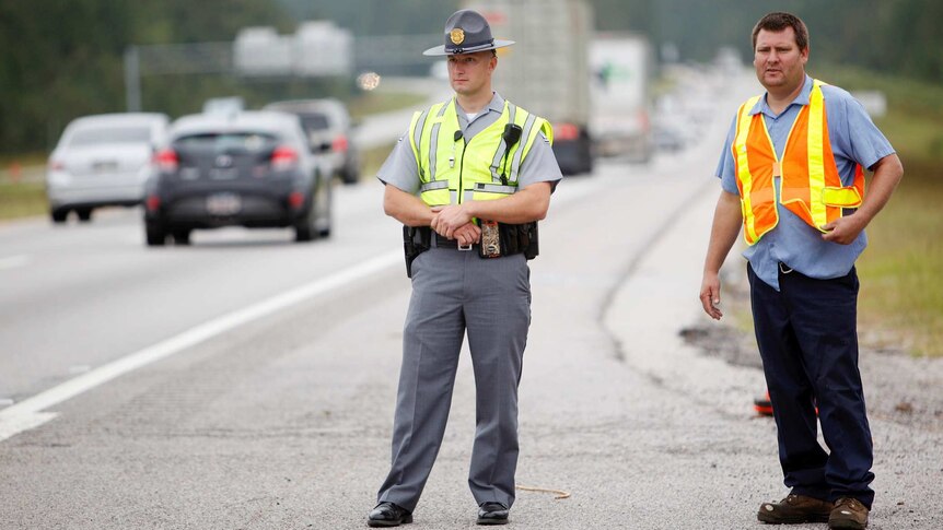 A South Carolina highway patrolman and Department of Transportation worker monitor traffic.