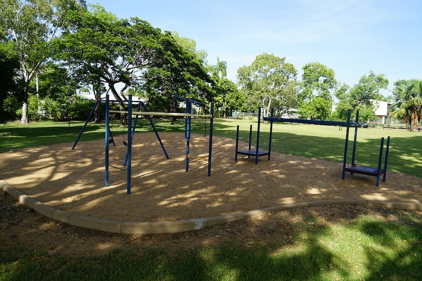 A small playground with swings, a see-saw and monkey bars is pictured