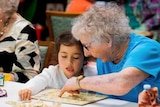 An elderly woman and young girl do a puzzle together