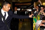 Tim Cahill hands a fan his scarf before boarding a plane to Brazil