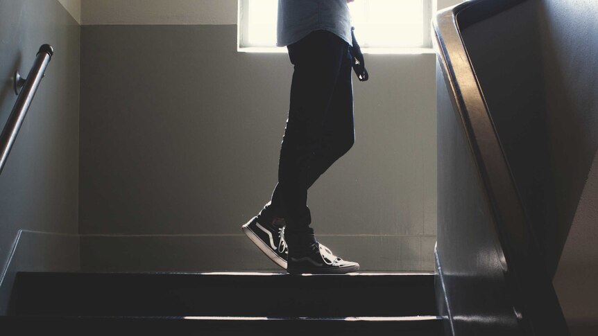 A student's legs are seen as they walk upstairs in a public looking building.