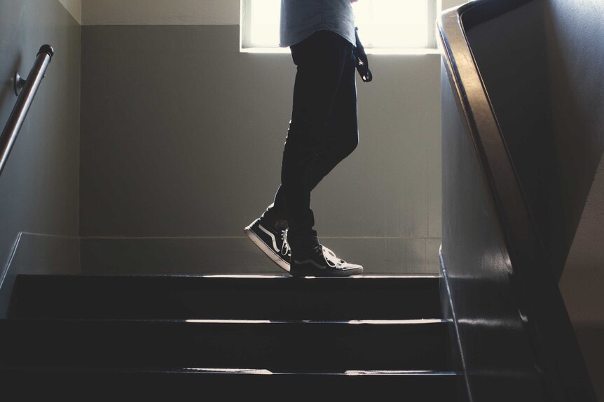 A student's legs are seen as they walk upstairs in a public looking building.