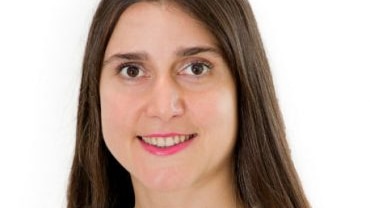 A headshot of a smiling woman with long brown hair