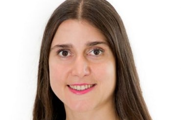 A headshot of a smiling woman with long brown hair