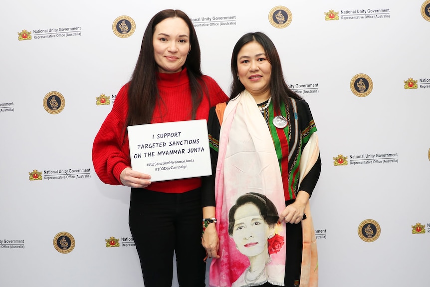 Two women of Burmese heritage standing with one holding a sign saying 'I support targeted sanctions'.