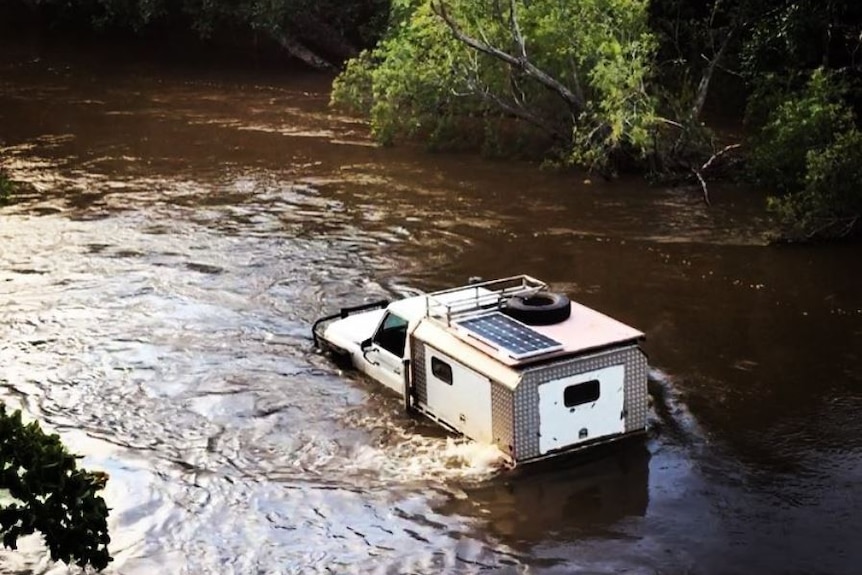 A car is bogged trying to cross floodwaters in North Queensland