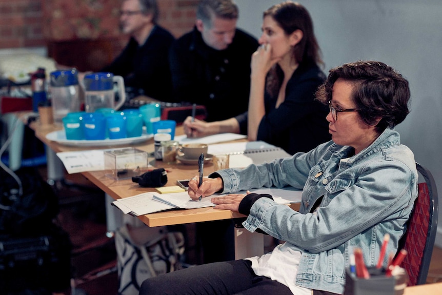 A woman takes notes on a piece of paper.