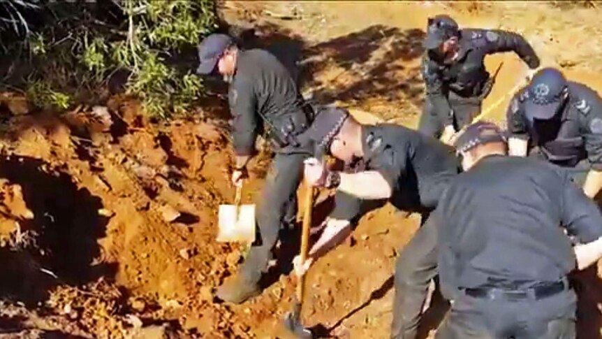 Police digging red soil.