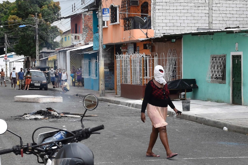 A woman walks past wearing a cloth around her head in a suburb of Guayaquil, Ecuador.