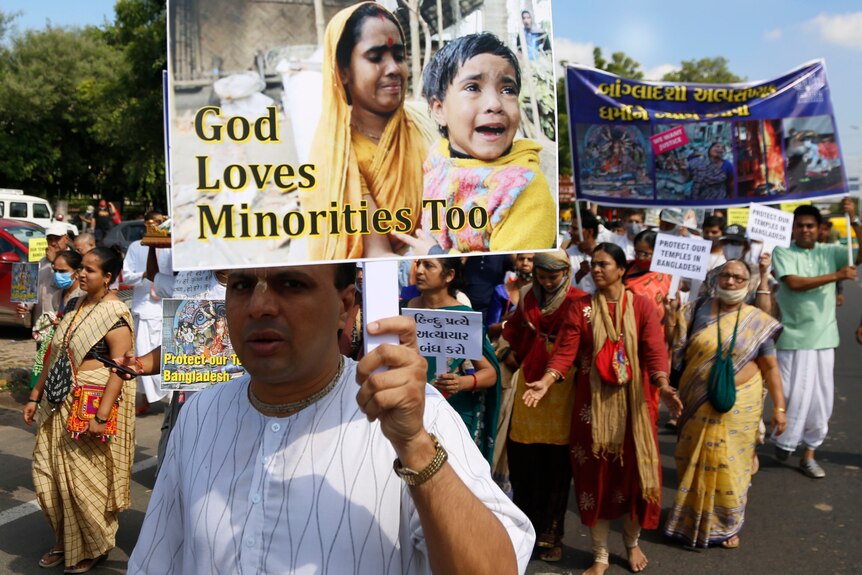 A large group protests with banners including "God loves minorities too".