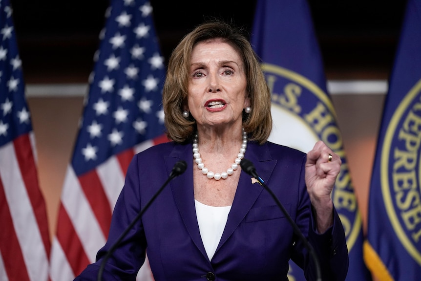 Speaker of the House Nancy Pelosi raises a fist as she speaks.