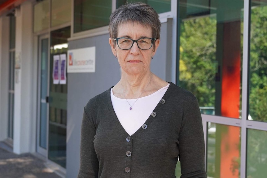 An older woman with glasses in front of a building.