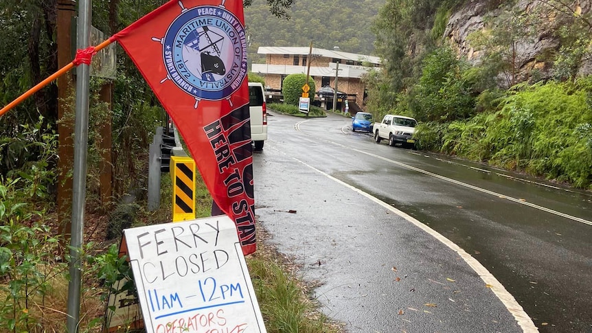 A corflute sign reading "Ferry Closed 11am-12pm" by the side of a road