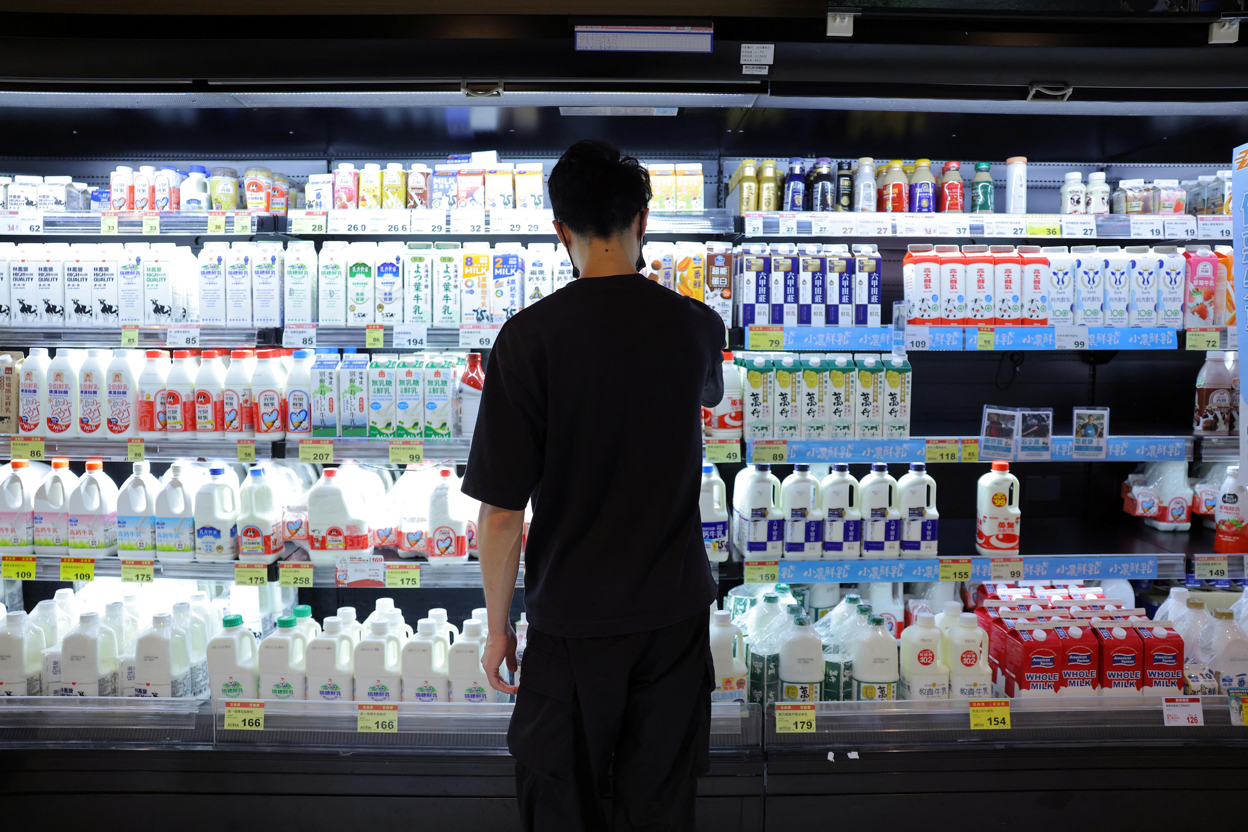 Un cliente se para frente a los productos lácteos expuestos en un estante de un supermercado PX Mart en Taipei.