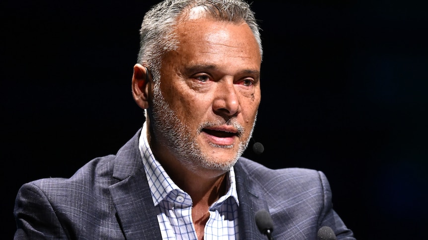 Journalist Stan Grant in a suit and shirt speaking at an event