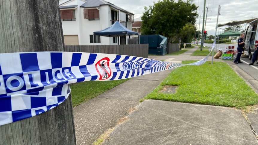 Police tape across a property with a police van in background.