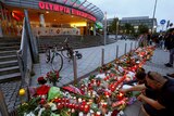 People lay flowers in front of Olympia shopping mall