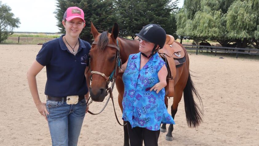 Lisa McManus stands next to a horse with her daughter Alice.