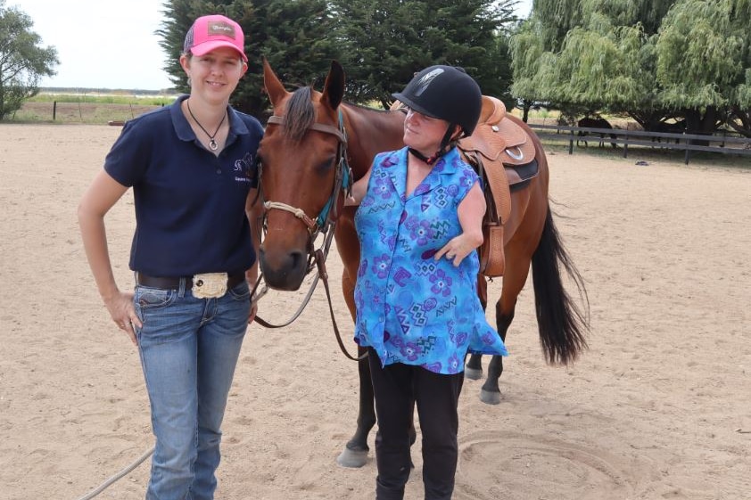 Lisa McManus stands next to a horse with her daughter Alice.