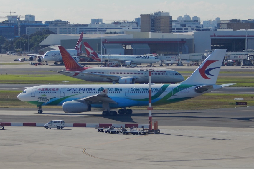 A China Eastern Airlines A330 Airbus sitting on the tarmac at Perth International Airport with other planes in the background.