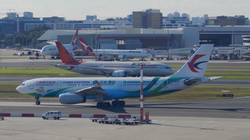 一架中国东方航空公司的A330空中客车坐在珀斯国际机场的停机坪上，背景是其他飞机。