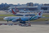 一架中国东方航空公司的A330空中客车坐在珀斯国际机场的停机坪上，背景是其他飞机。