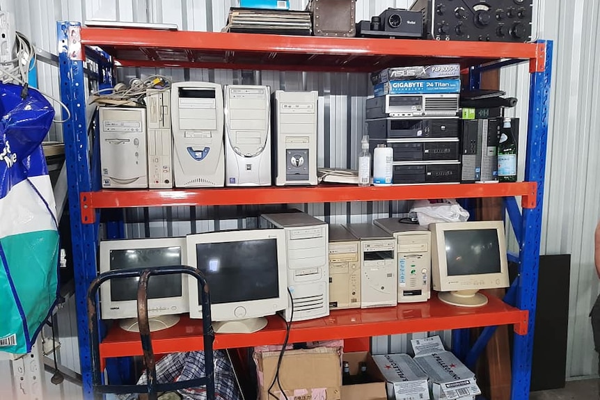 Two shelves packed with computer hard drives and monitors. 