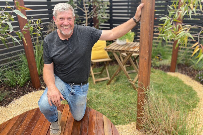 Man kneeling in a garden, smiling, happy teacher 