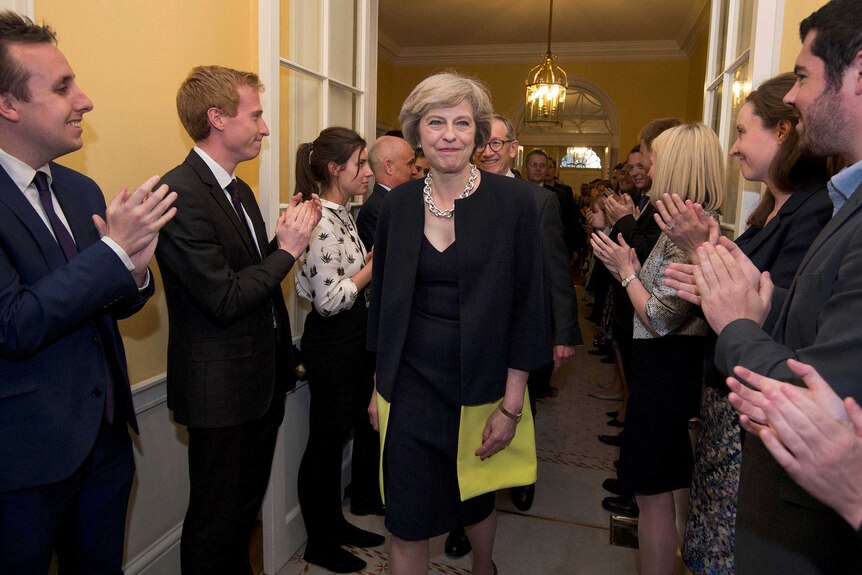 Theresa May is applauded as she walks into 10 Downing Street.