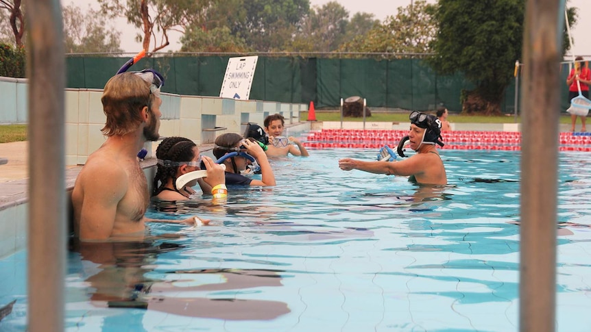 A photo of the underwater hockey team lined against the end of the pool.