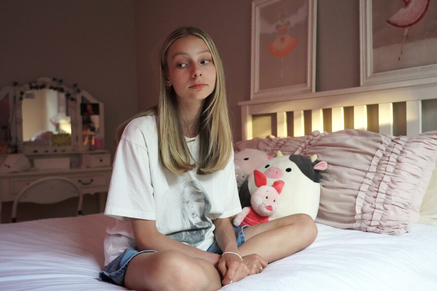 A Perth teenage girl sits on her bed