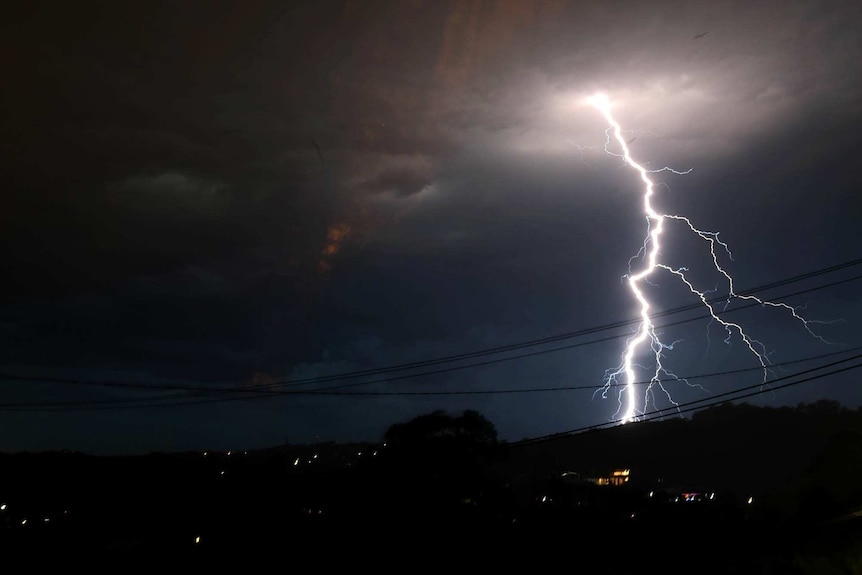 A lightning bolt illuminates the sky over a  city.